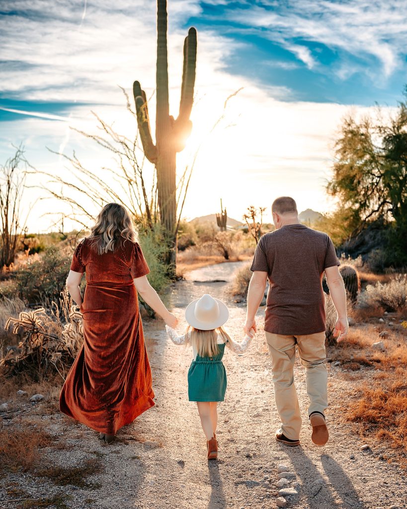 Boho family of three walking away from the camera among the cactus & Arizona scenery. 