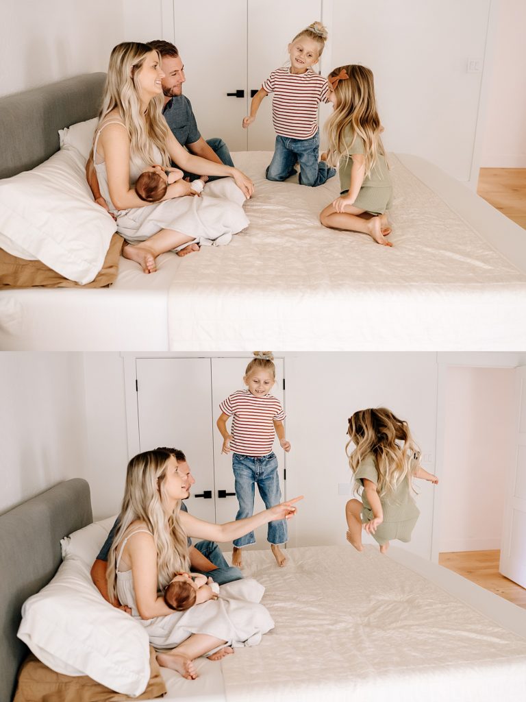 Two little girls jumping on the bed with parents holding new baby nearby. 