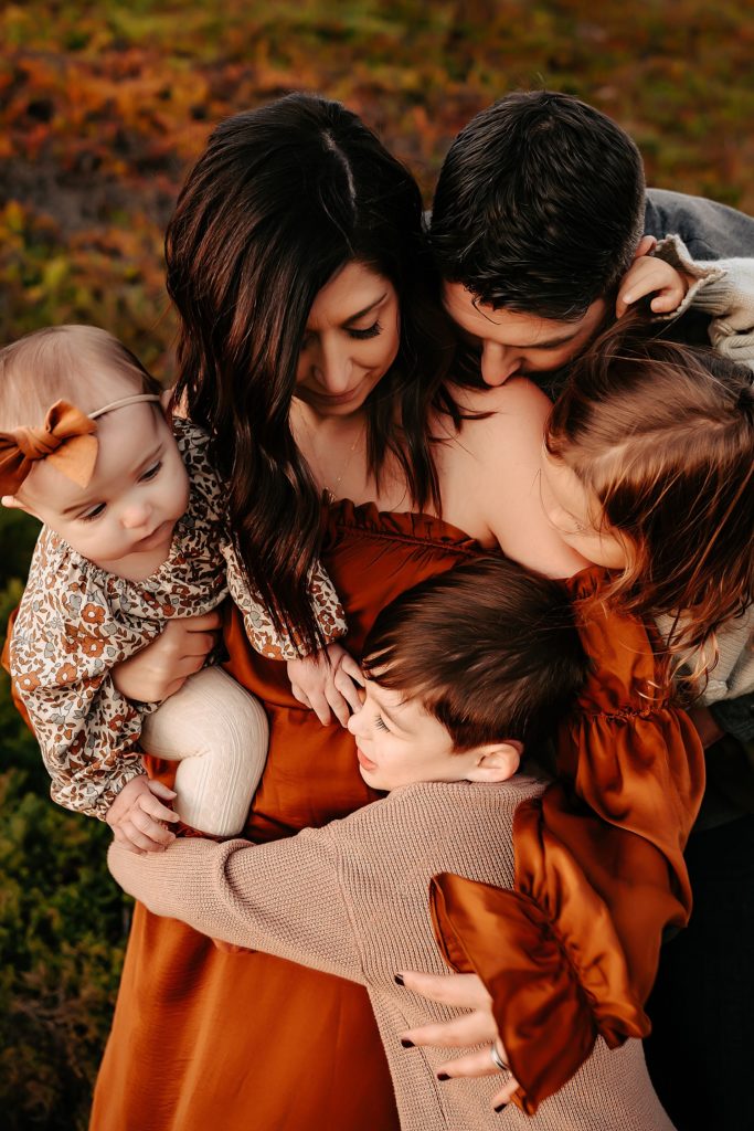 Family of five snuggling close for their family session on the coast. 